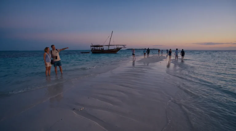 Visitors walking on Nakupenda sandbank at sunset with a traditional dhow moored offshore